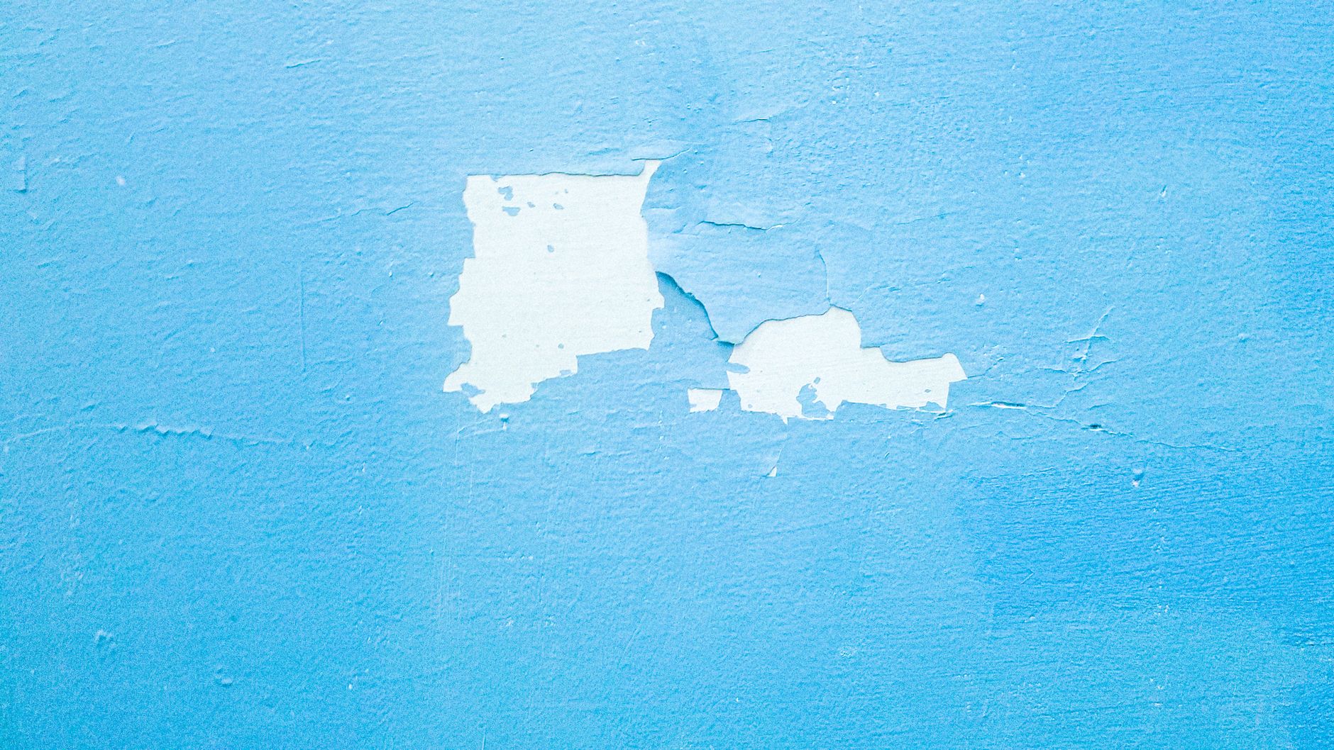 Close-up of a textured blue wall with peeling paint revealing layers beneath in Riverside, CA